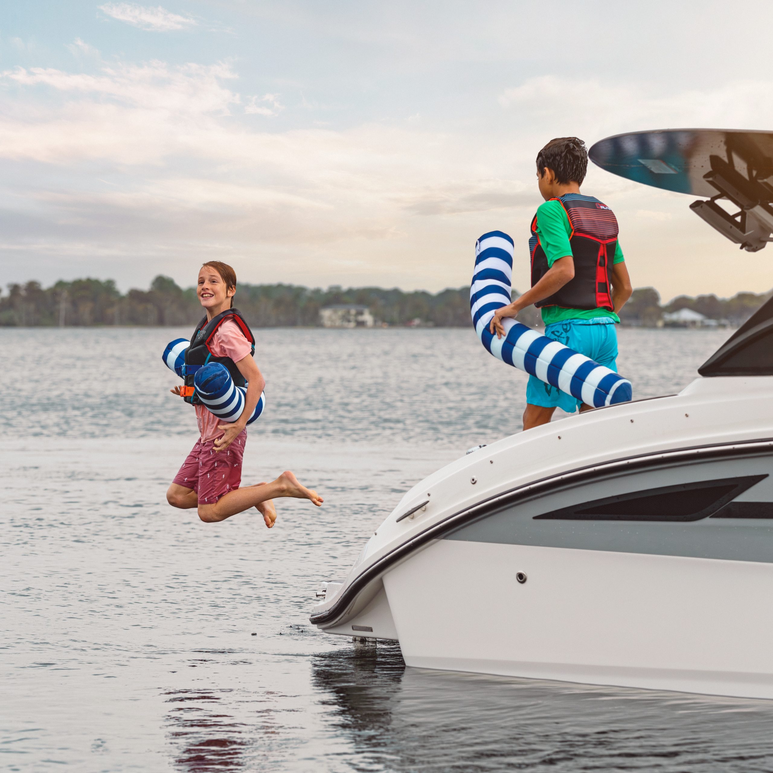Boy jumping in the water from an SDX 270 Surf while his friend watches